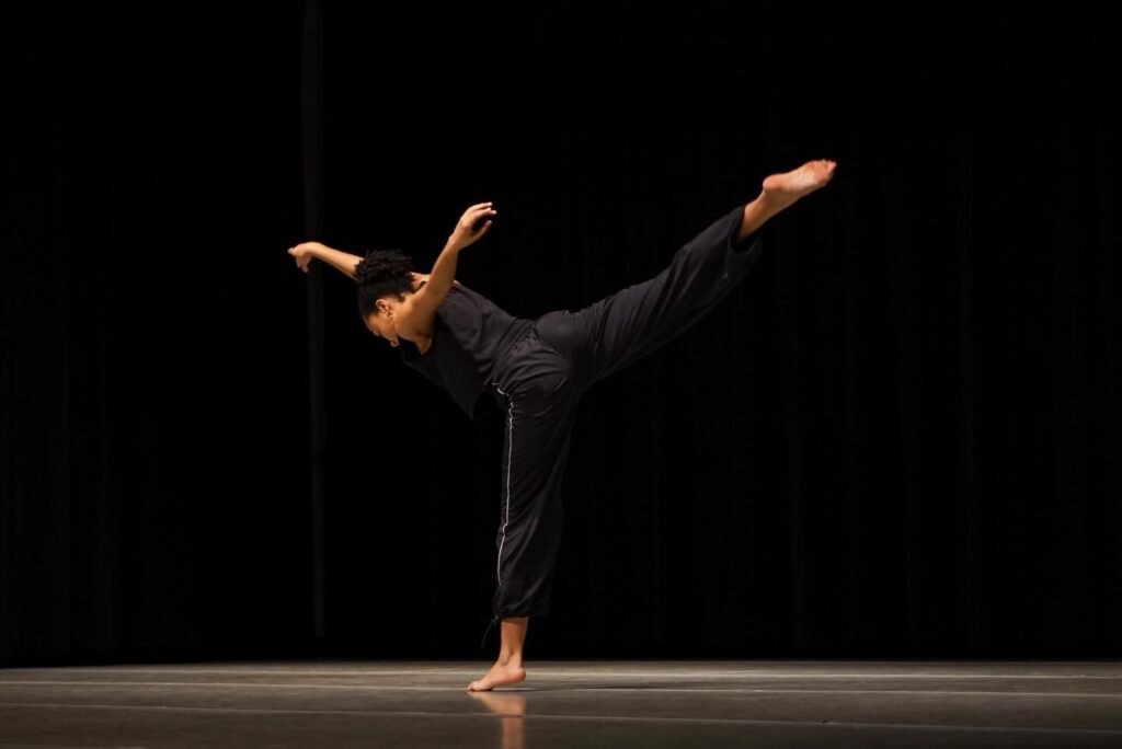 Contemporary dancer balances on one leg with the other extended behind in a controlled arabesque.
